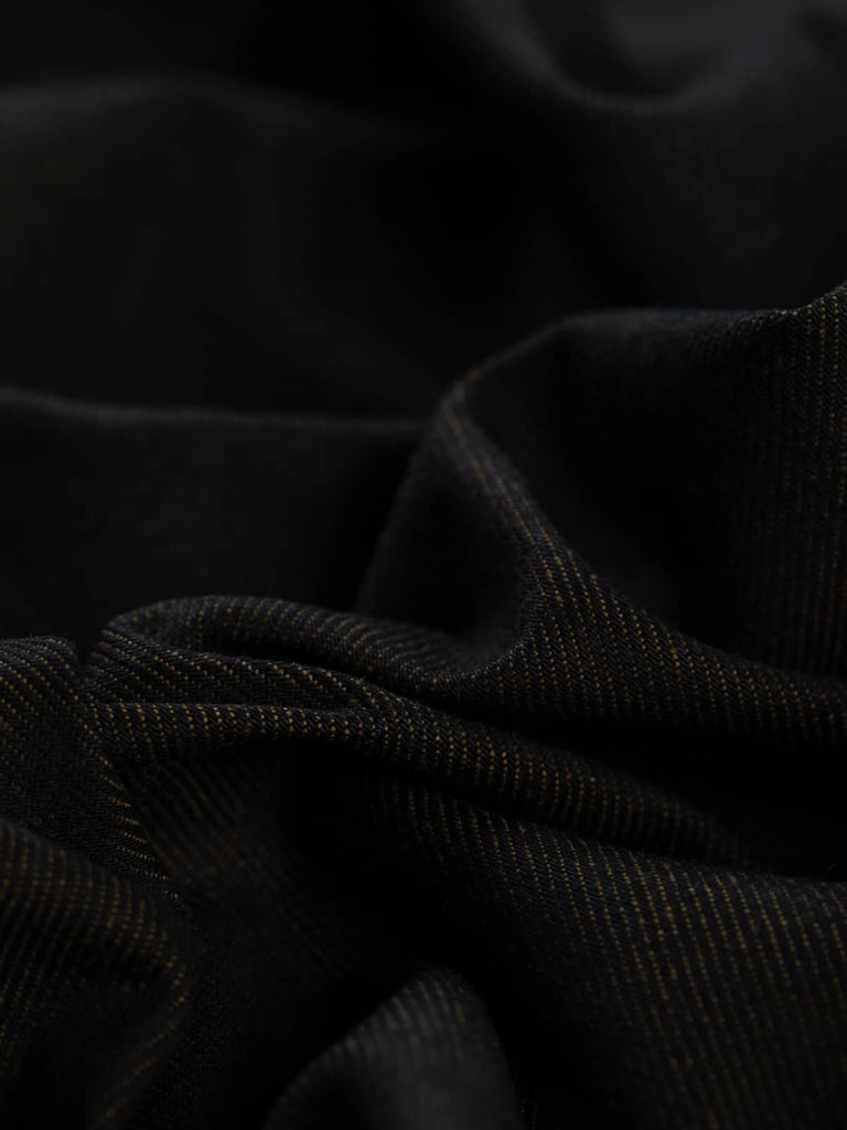 Cocoa Shot denim presents a deep brown-black hue with a subtle shot effect, blending black warp threads with soft chocolate brown weft for a sophisticated, rich tone.