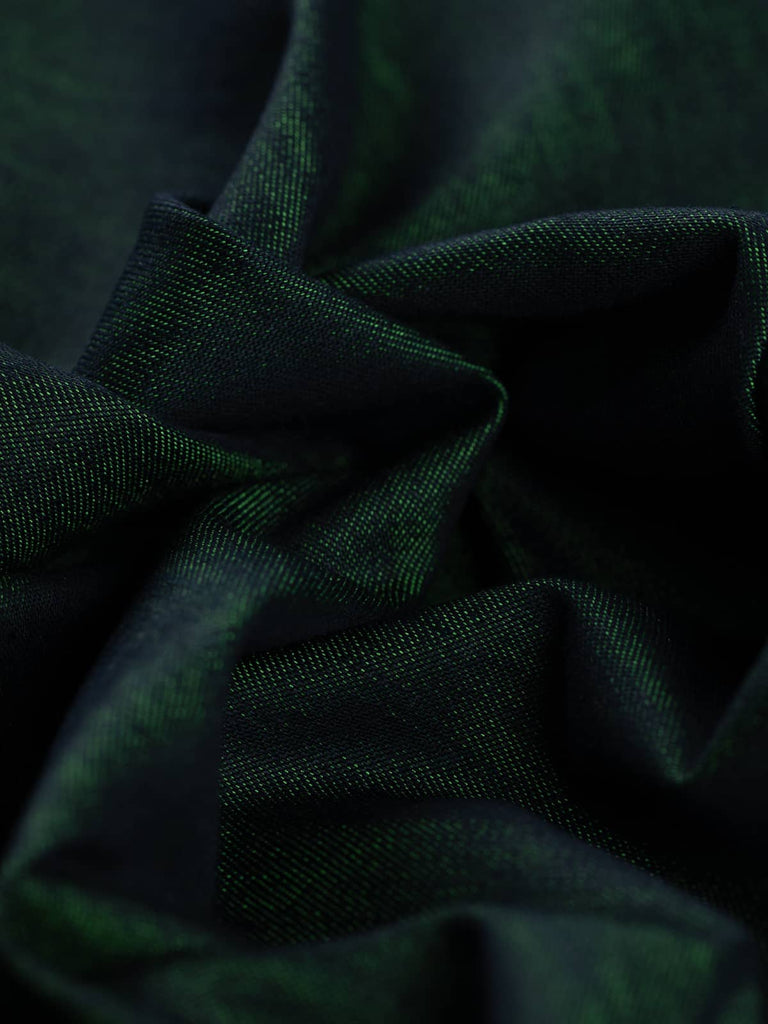 A close-up of Emerald Gleam Denim fabric twisted at an angle, showcasing its striking shot effect where deep indigo navy meets gleaming emerald green. The twill weave and subtle sheen of the polyester threads create a luxurious, dynamic look.