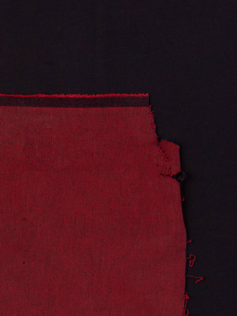 Overhead flat shot of Raspberry Shot Denim fabric, capturing the sophisticated interplay between dark navy warp and raspberry-pink weft, producing a luxurious shot-effect surface with refined structure.
