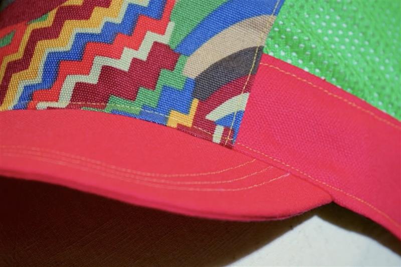 Colorful zigzag-patterned visor on a red cap with a green background - focus on top stitching