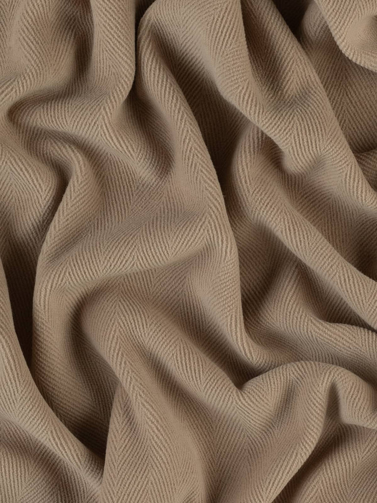 Image showcasing a luxurious wool fabric in a warm sandy beige shade, highlighted by a prominent 6cm herringbone weave. This dense, double-faced fabric is perfect for crafting stylish winter garments, utility jackets, and home decor items like cushions and footstools.