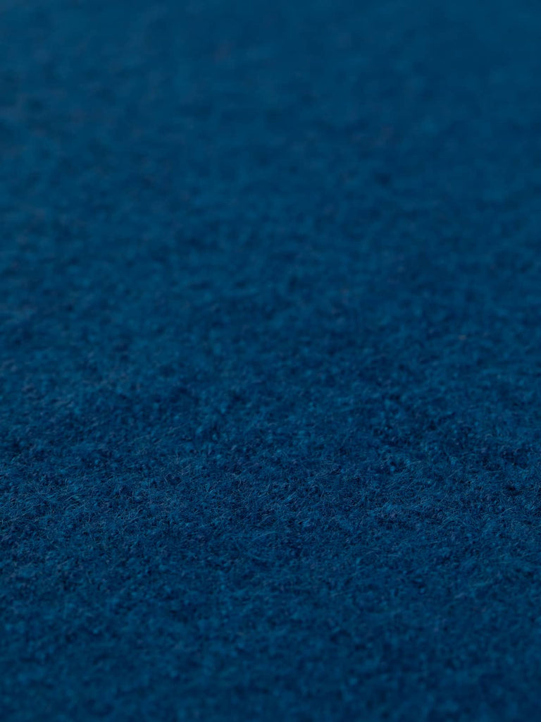 Close-up angled shot of Deep Ocean boiled wool fabric laid flat, showcasing its rich, multi-toned blue-green depth. Elevate your designs with this luxurious fabric—order yours today.