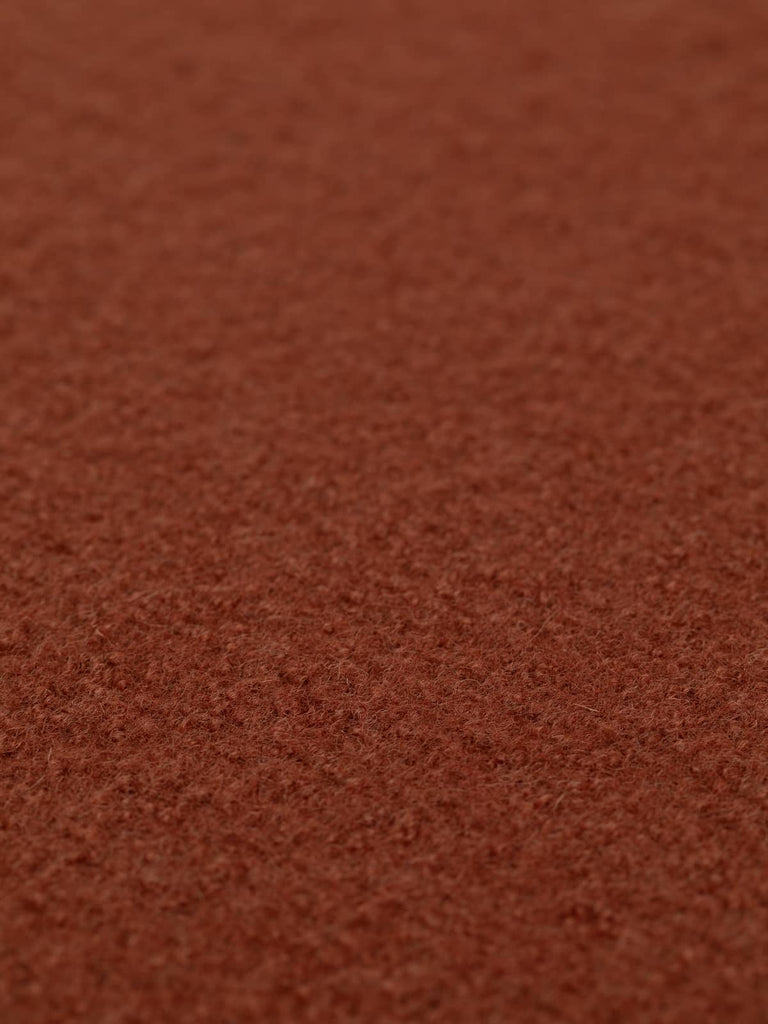 Angled close-up of Cinnamon Spice boiled wool fabric laid flat, highlighting its soft, slightly textured surface and deep, warming rust-red hue, perfect for autumn-inspired clothing and accessories.