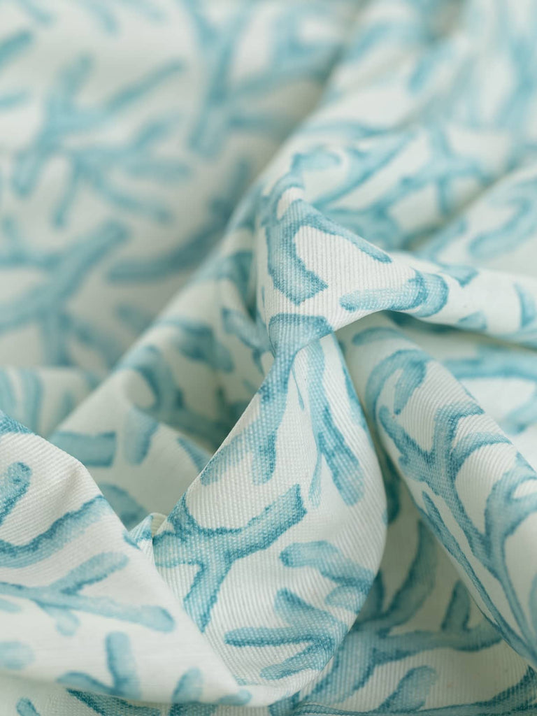 Aqua Coral Reef is a medium-weight, water-resistant fabric featuring a delicate aqua-blue coral bract design on a natural white background. Ideal for outdoor use and bathroom accessories, this fabric's acrylic coating ensures durability and easy cleaning.