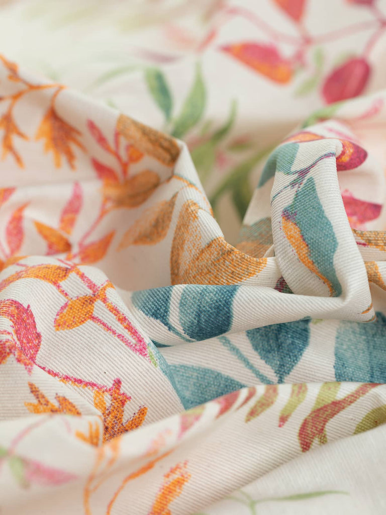 Summer Meadow features a pale cream background with a vibrant, watercolor-style pattern of fern and grass-like fronds in hues of tangerine, raspberry, teal, and turquoise. This water-resistant fabric is perfect for outdoor furniture, table covers, and wipeable bags.