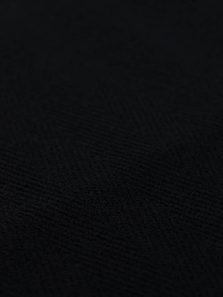  Close-up of a deep navy wool fabric featuring a 6cm jumbo herringbone pattern. This heavy 100% wool fabric is perfect for creating tailored overcoats, corporate uniforms, and luxurious upholstery with its soft yet sturdy texture.