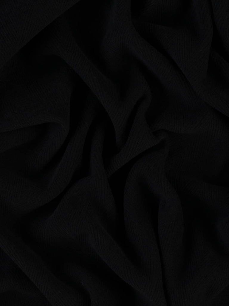 Image of an ultra-dark black wool fabric featuring a 6cm jumbo herringbone weave. This double-faced, heavyweight material has a dense, felted texture, perfect for durable winter coats, work jackets, or upholstery projects.