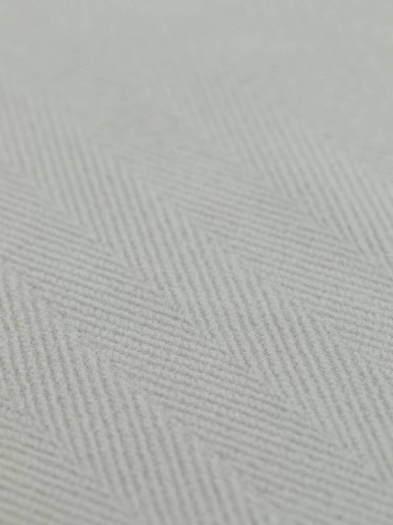  A close-up of silver wool fabric showcasing a 6cm herringbone pattern. This heavy, 100% wool fabric features a flawless light grey hue, perfect for elegant overcoats, winter jackets, or sophisticated upholstery projects.