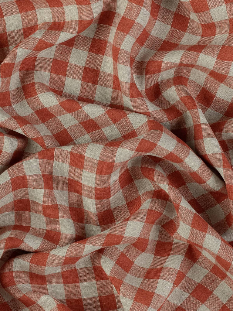 Top-down view of the fabric twisted gently to display the rich cinnamon and beige check pattern. The subtle texture and casual drape reflect the fabric's easygoing charm and natural linen character.